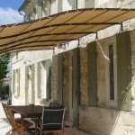 Light pergola above the entrance - an awning is stretched over a metal frame