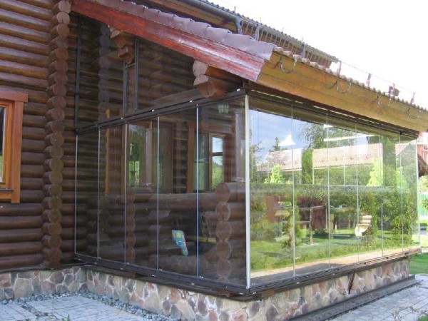 Frameless glazing of the veranda in combination with a log house is not the best solution