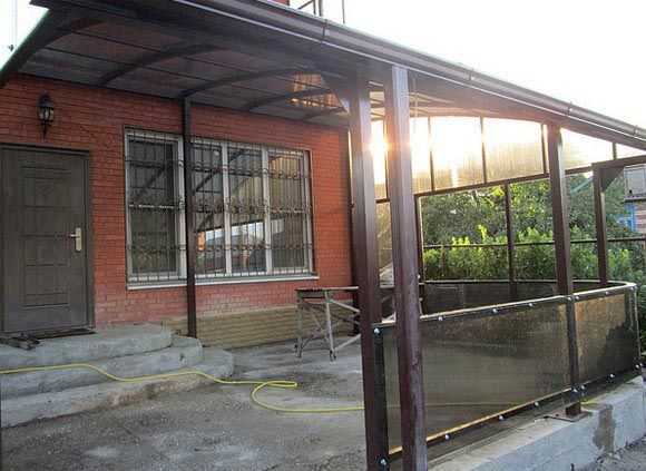 A polycarbonate veranda attached to a brick house. The whole frame is assembled from a shaped tube