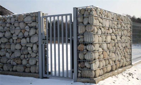 Stone fence built using dry technology - no mortar - boulders are poured into a grid
