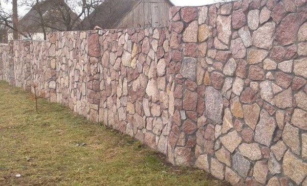Stone fence. This one is definitely made of stone and correctly tied up: there is a little mortar between the stones, and this indicates a good quality of work