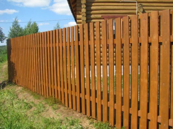 A simple picket fence made of boards impregnated with a toning antiseptic looks solid