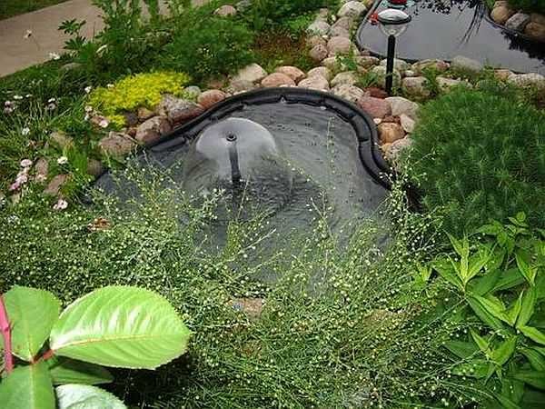 A plastic container is visible, and the pump is at the bottom, right in the place where a pipe sticks out of the water
