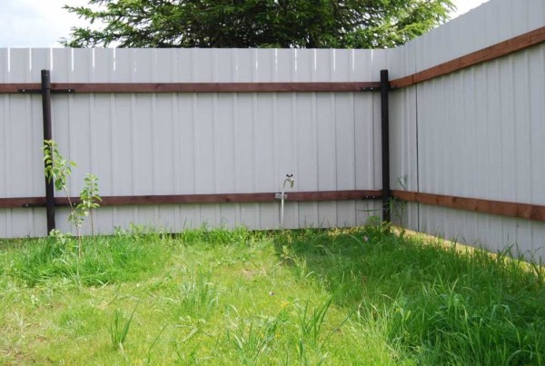 Fence made of corrugated board on wooden logs