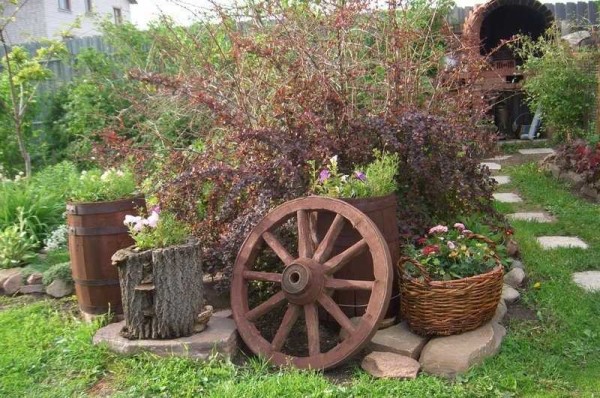 Rustic garden design is easily recognizable by the presence of wheels from carts, baskets, ceramic dishes, which is used in the most unexpected ways