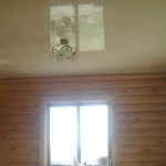 Glossy stretch ceiling in a log house