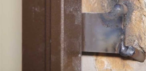 Weld to two pieces of reinforcement driven into the wall
