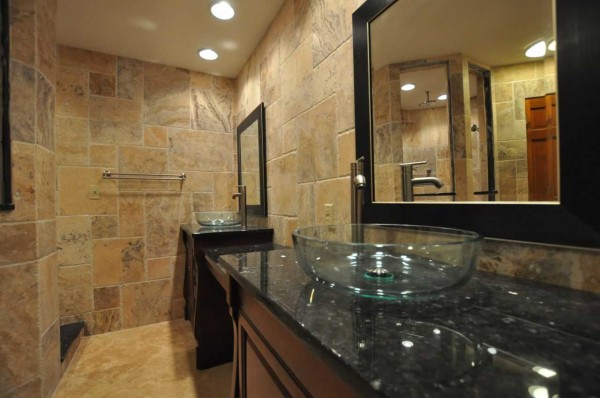 On the walls - natural stone, unusual furniture and a glass sink - a stylish interior