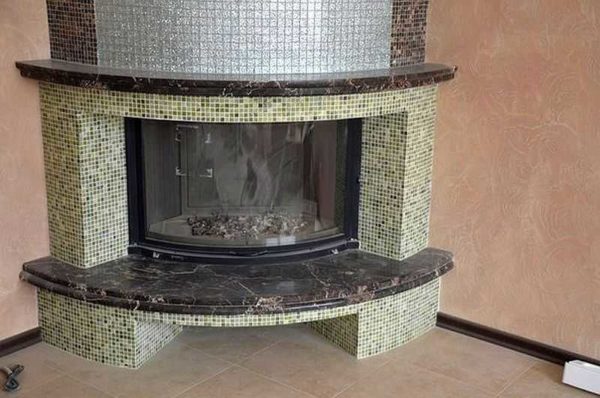 Decorating a fireplace with mosaic is especially good on rounded shapes, where other materials are very problematic to use.