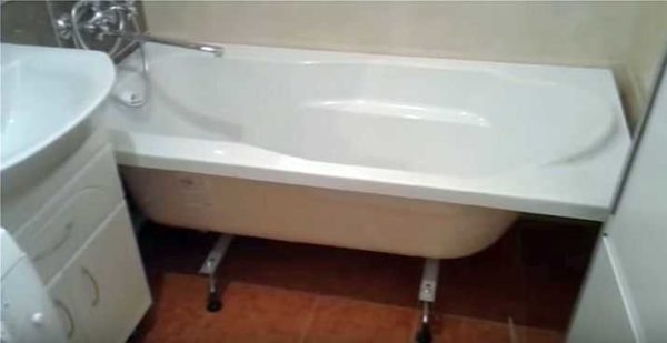 Installation of an acrylic bathtub on legs is completed