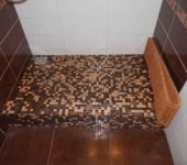 It is not at all necessary to make a drain in the center - it can easily be shifted to any wall. In this case, the farthest wall from the entrance was chosen so that there is less possibility that water will pour out of the booth