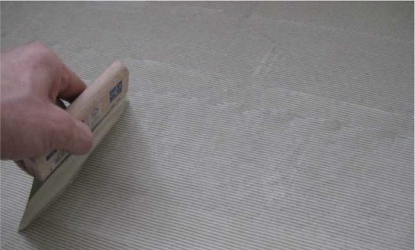 The adhesive is spread over the floor with a notched trowel with a very fine tooth