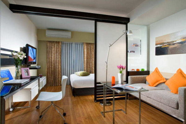 A bed in a living room with a dedicated bedroom is usually placed away from the entrance.