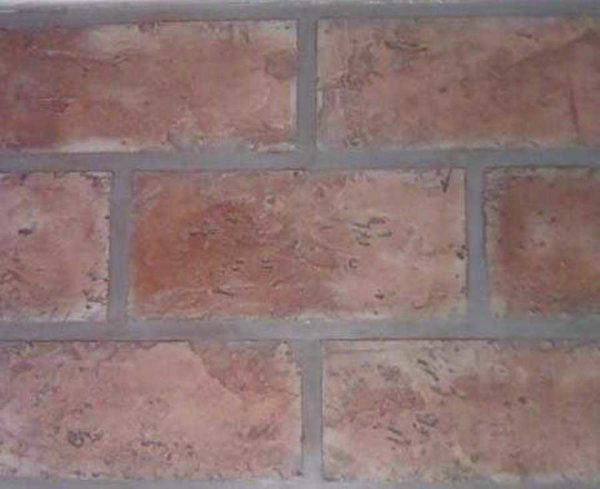 It looks like a mixture of simple textured plaster and roller. Quite a plausible imitation of brick for interior decoration